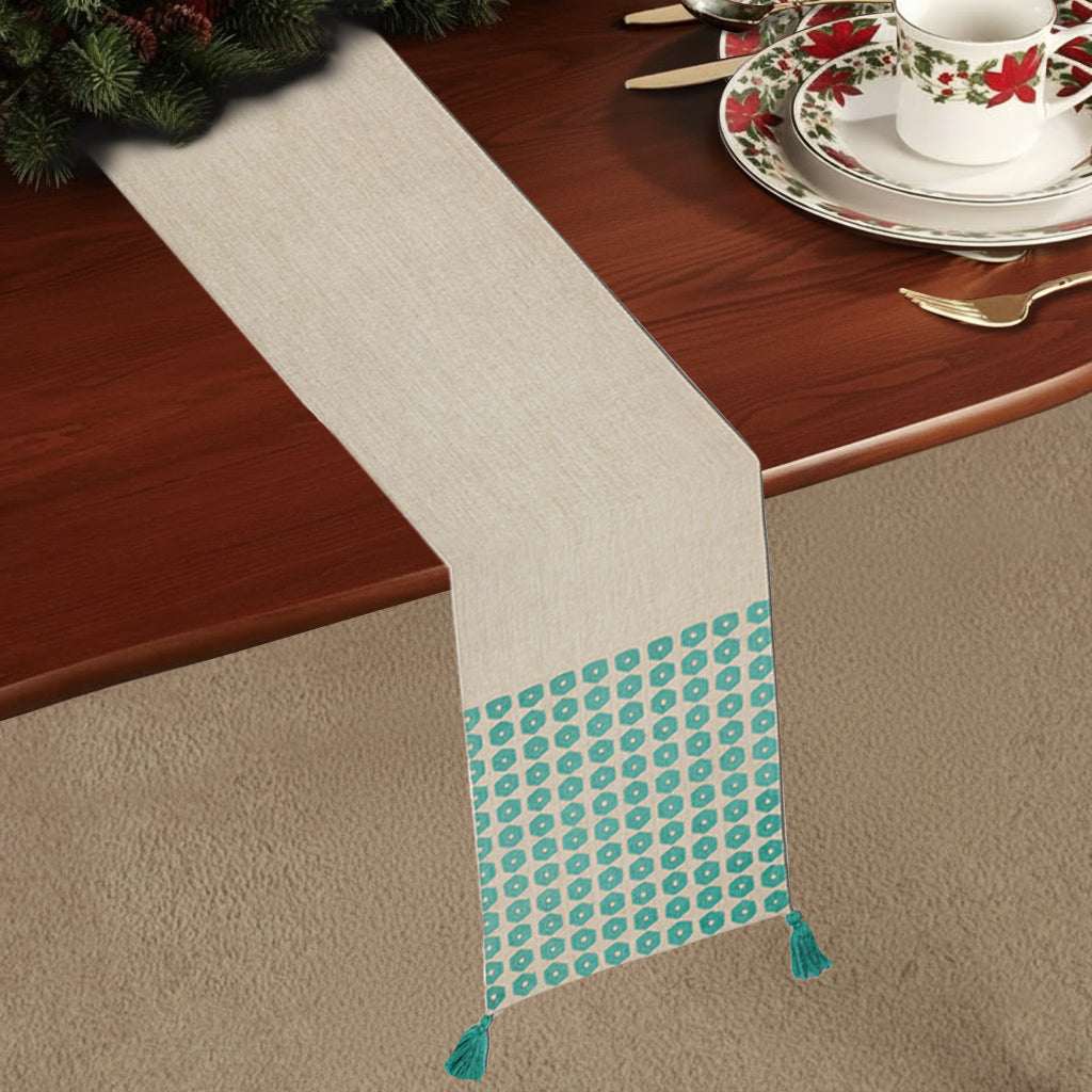 Beige chambray table runner with green embroidered hexagons and tassels on each corner